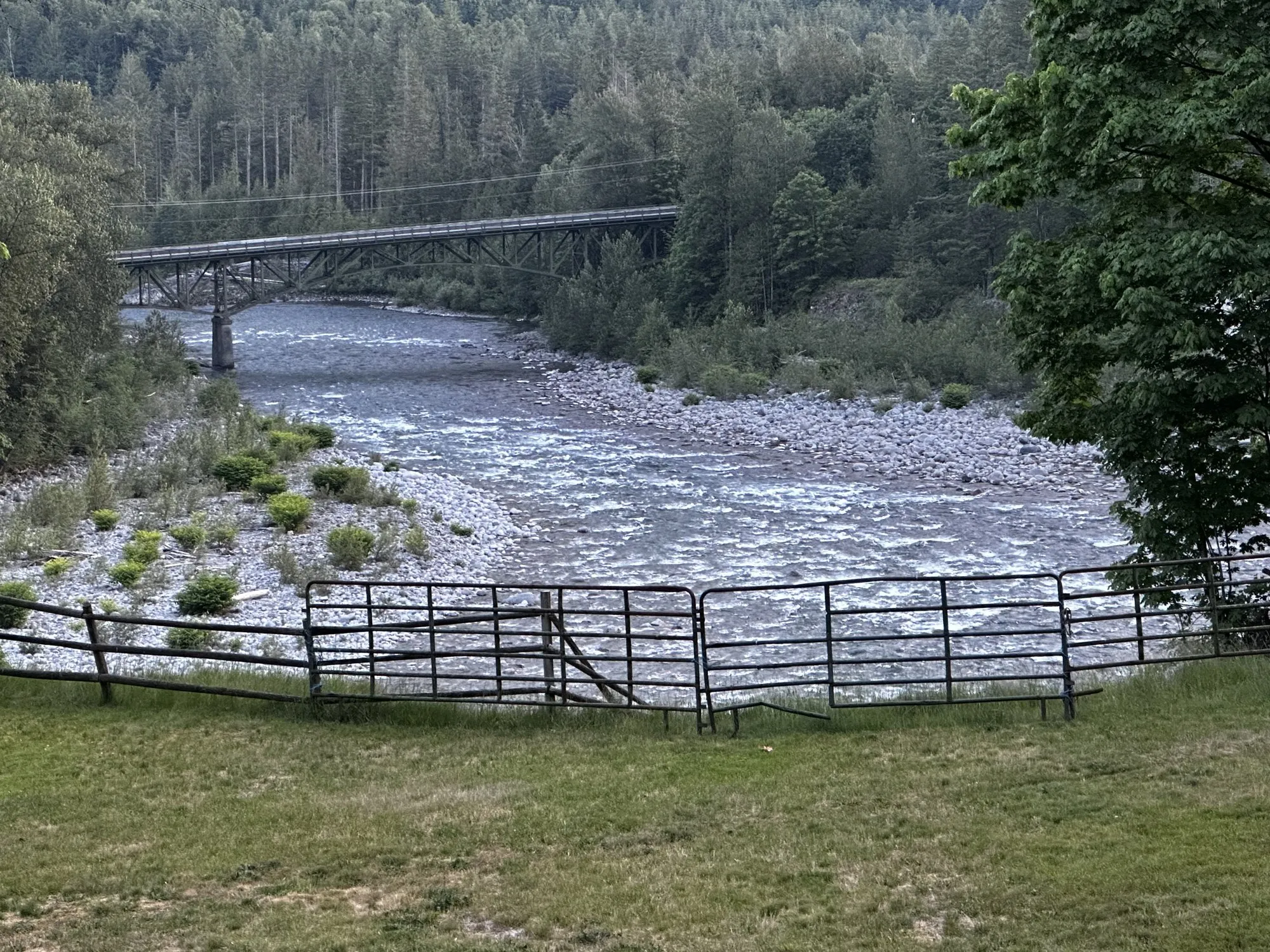 The Skykomish River winding past the property, with a steel bridge in the distance and pasture in the foreground